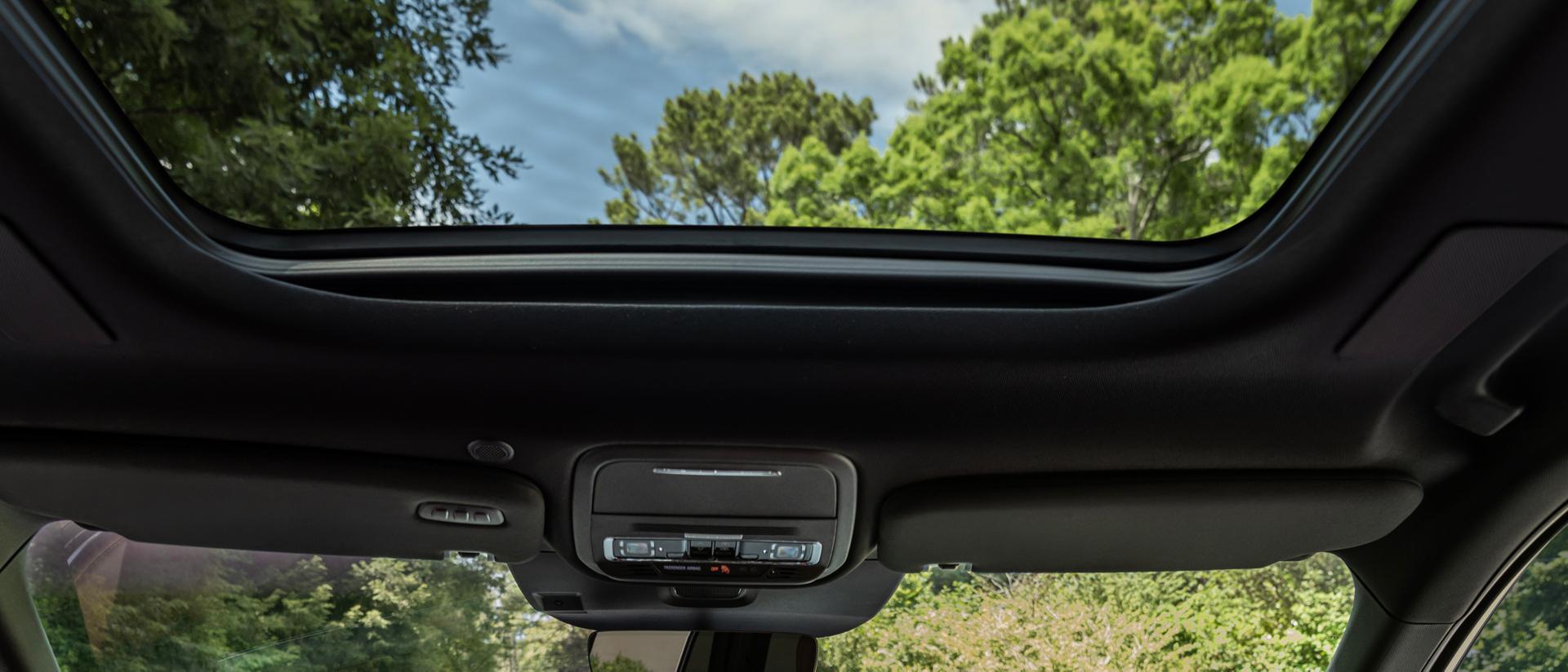 Une forêt luxuriante est visible à travers le pare-brise avant et le toit panoramique Vista Roof® d’un Lincoln Aviator® 2027