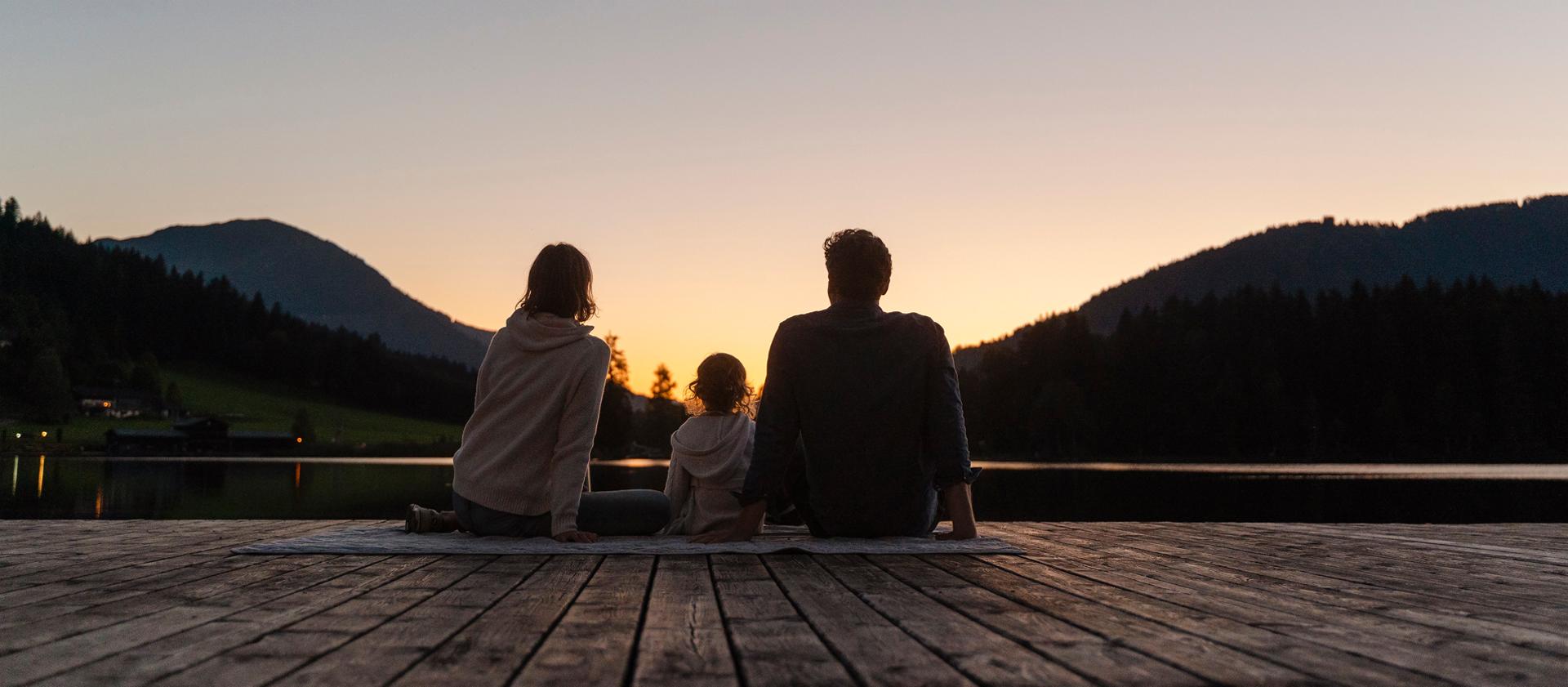Une famille assise à l’extérieur au coucher du soleil, dans l’attente du lever de la lune