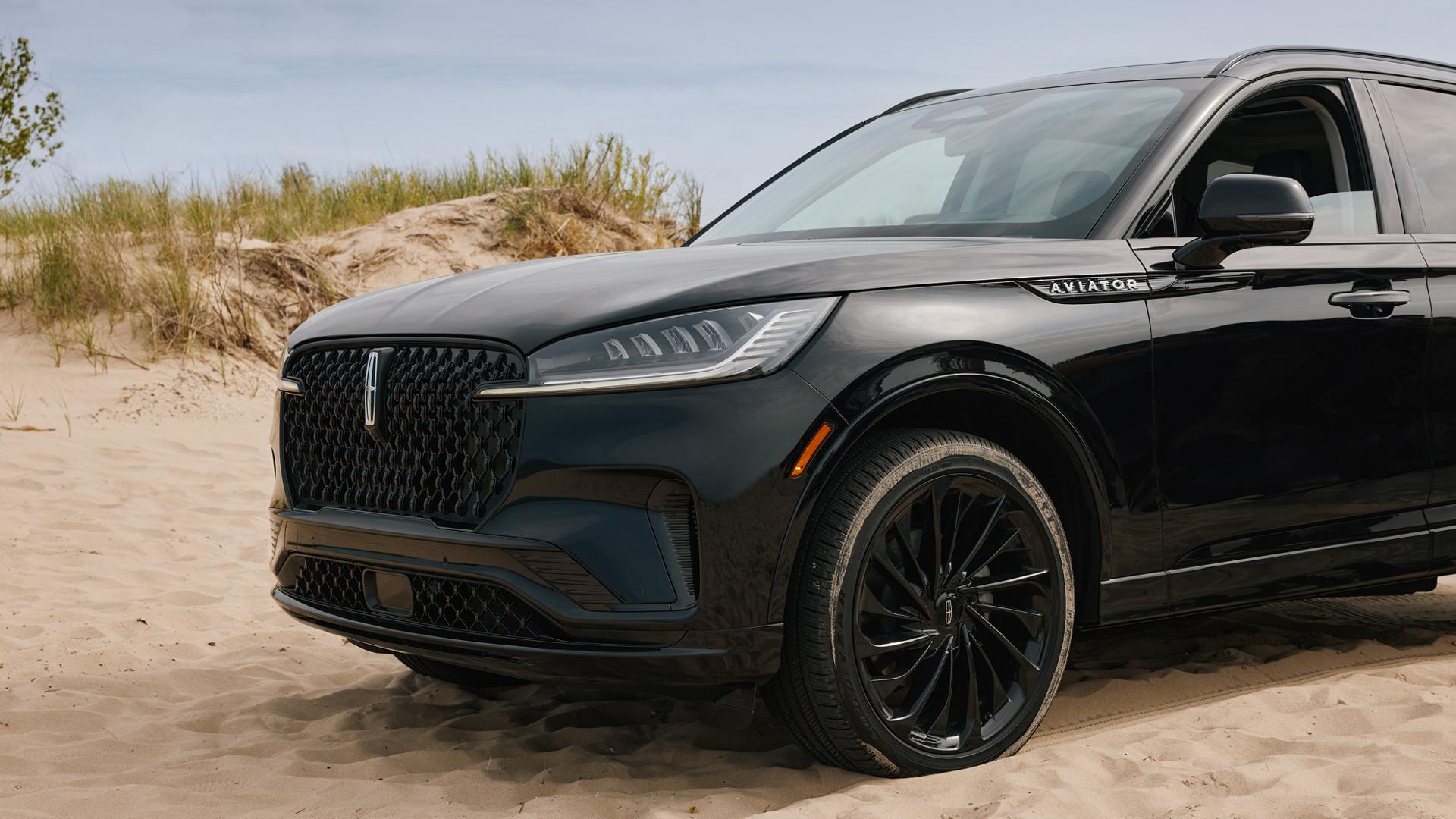 Un Lincoln Aviator® 2027 stationné près de dunes de sable au bord d’un lac