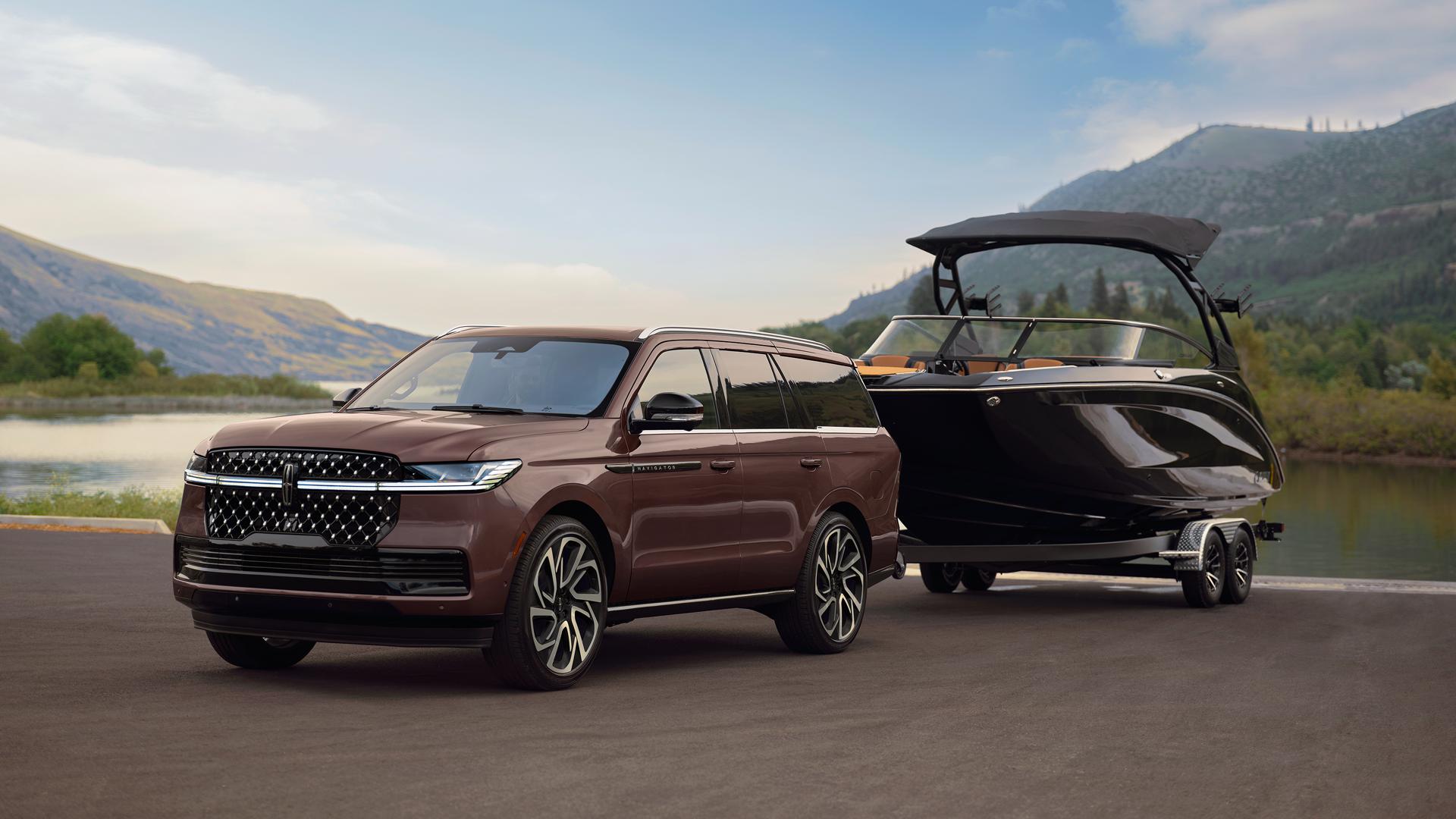 Un VUS Lincoln Navigator® 2027 avec un bateau sur une remorque est stationné sur une rampe de mise à l’eau panoramique.