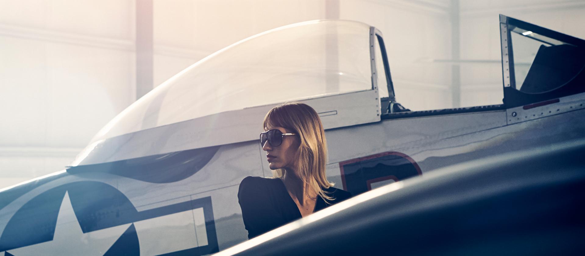 Une femme devant un avion d’époque dans un hangar privé