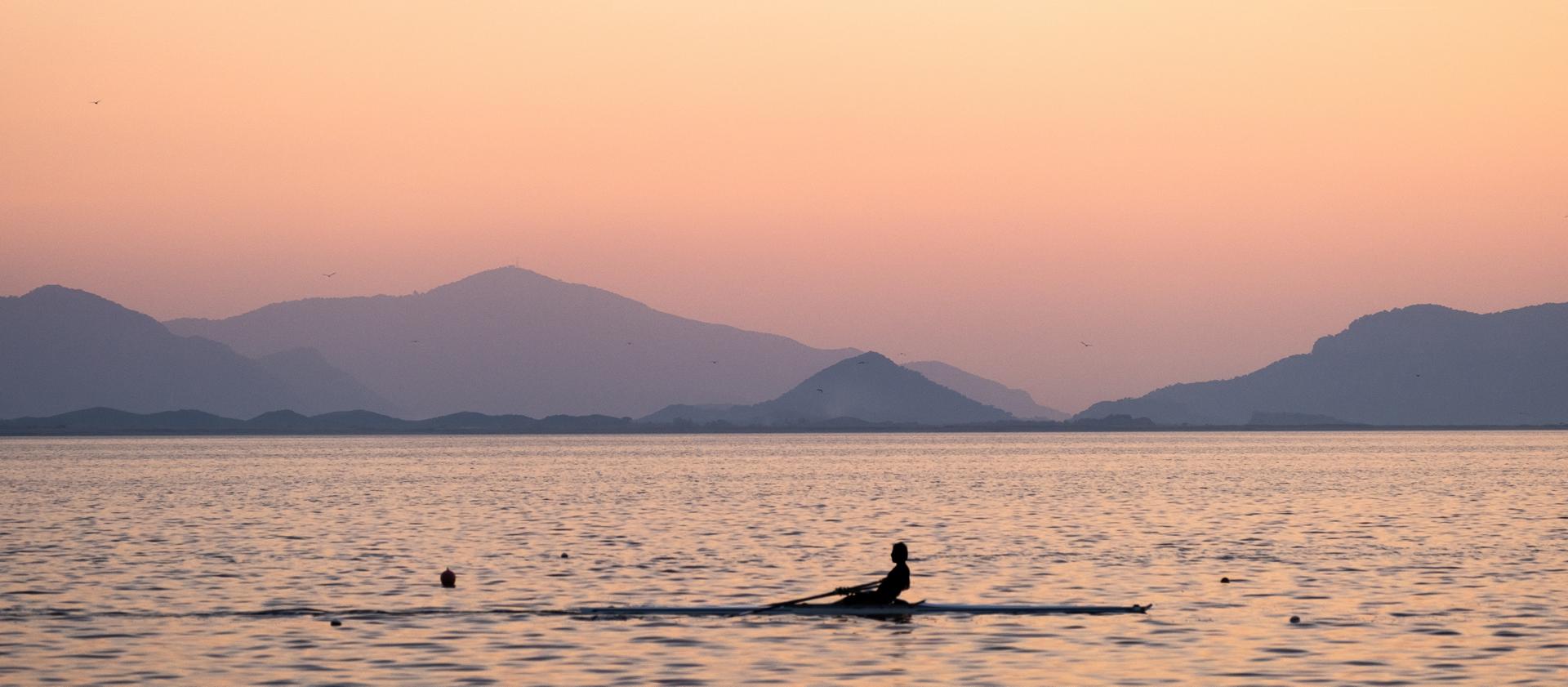 Une personne rame un bateau d’aviron sur l’océan le matin