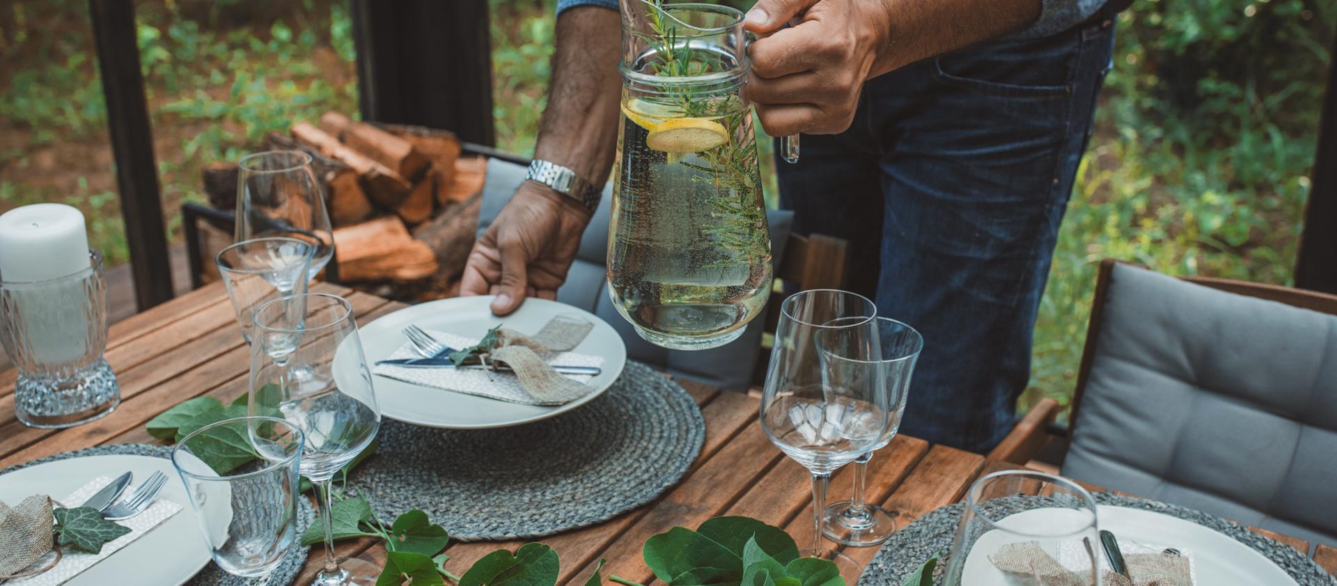 Un homme dresse une table à l’extérieur en prévision de l’arrivée de ses invités
