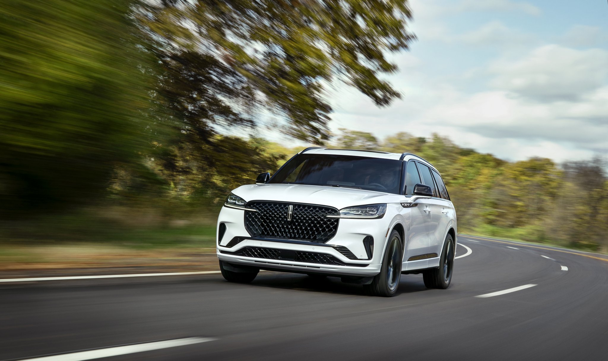 Un VUS Lincoln Aviator® 2026 circulant sur une route bordée d’arbres