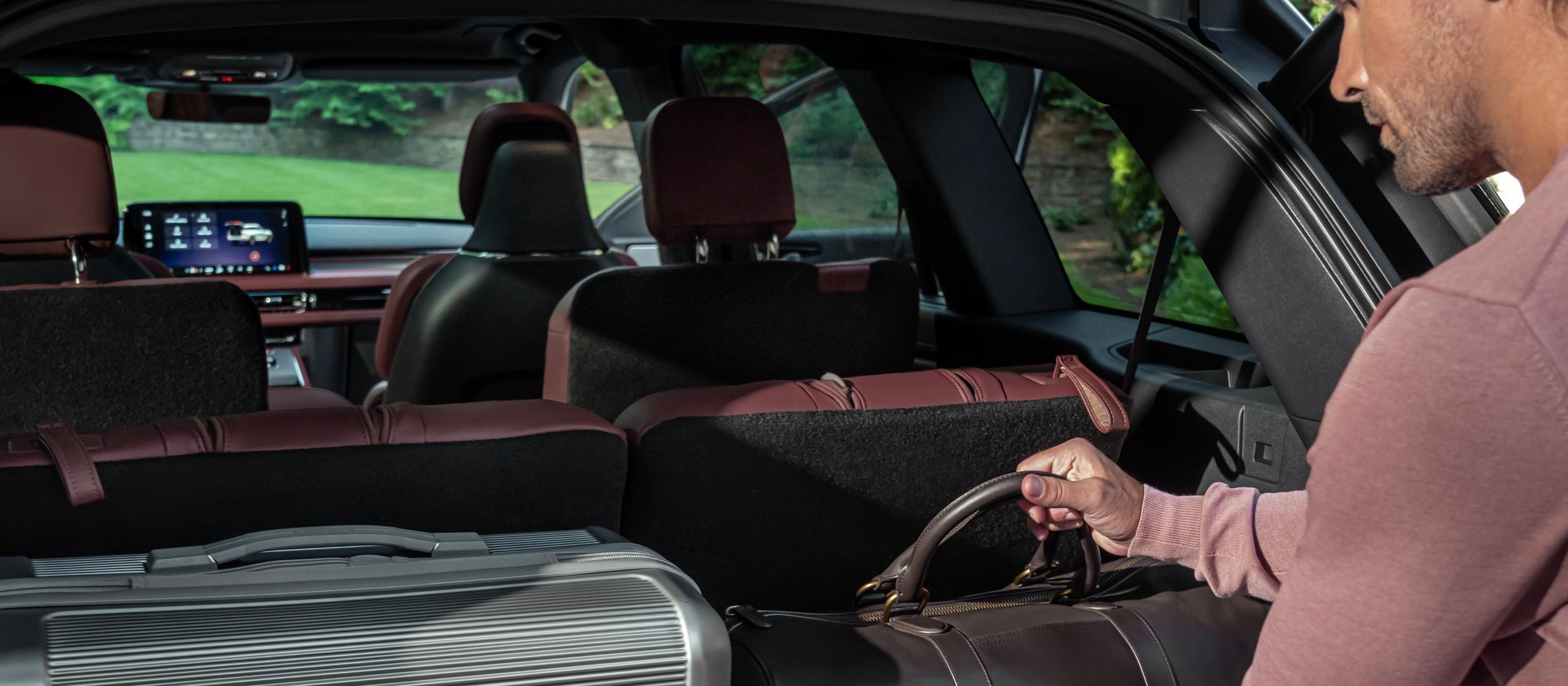 Une personne charge un sac en cuir dans la zone de chargement arrière d’un Lincoln Aviator 2026