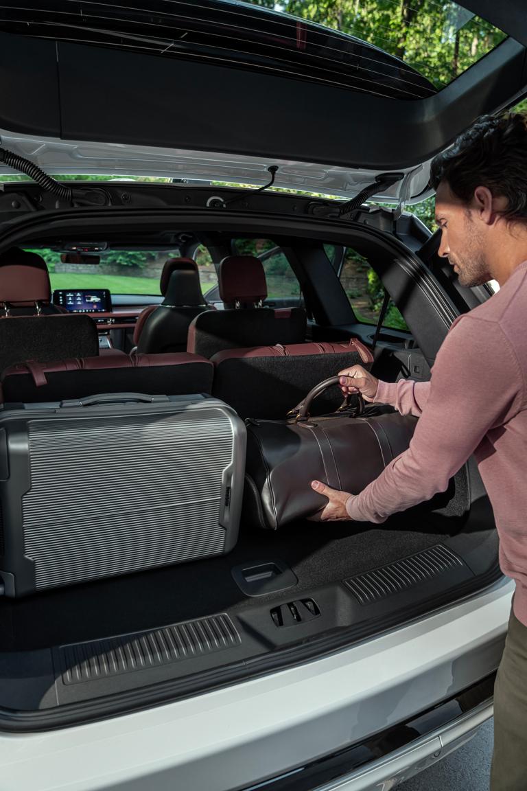 Une personne charge un sac en cuir dans la zone de chargement arrière d’un Lincoln Aviator 2026