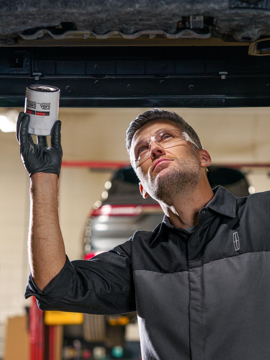 Un technicien Lincoln travaillant sur un véhicule depuis le dessous.