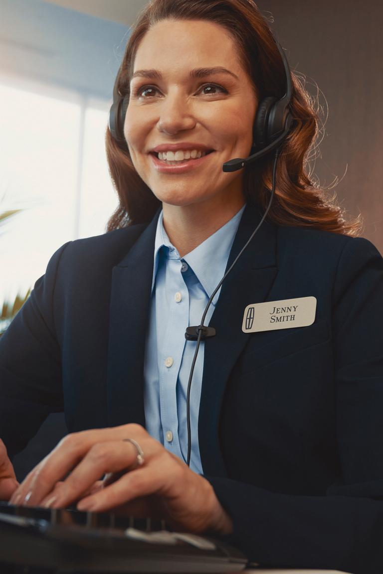 Un agent de soutien portant un casque d’écoute à un bureau avec le logo Lincoln visible en arrière-plan