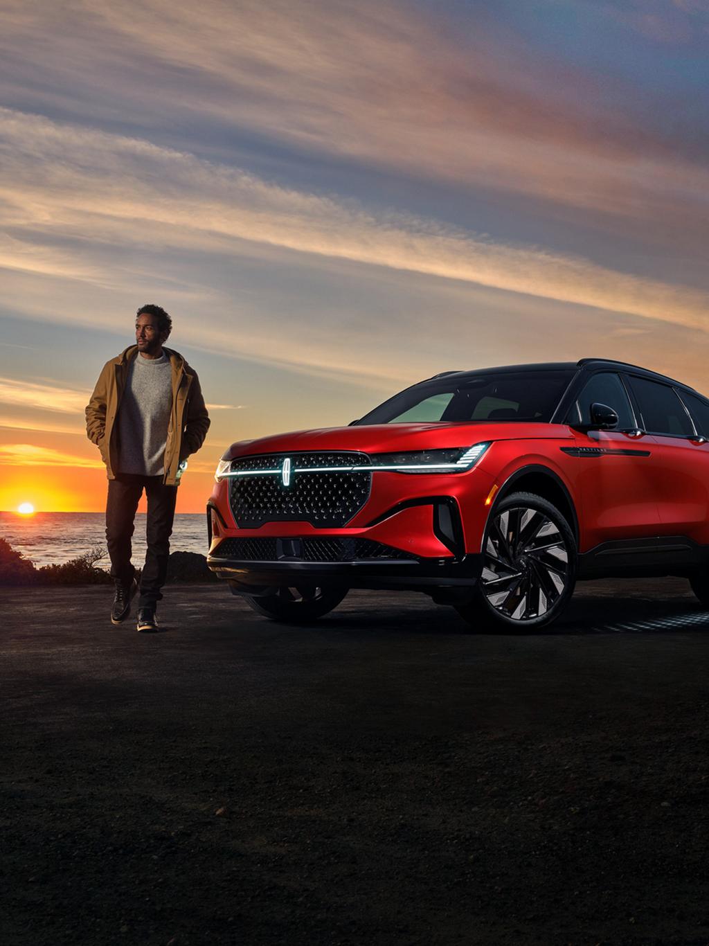 Un homme debout à l'extérieur d'un Lincoln Nautilus stationné près d'un cours d'eau.
