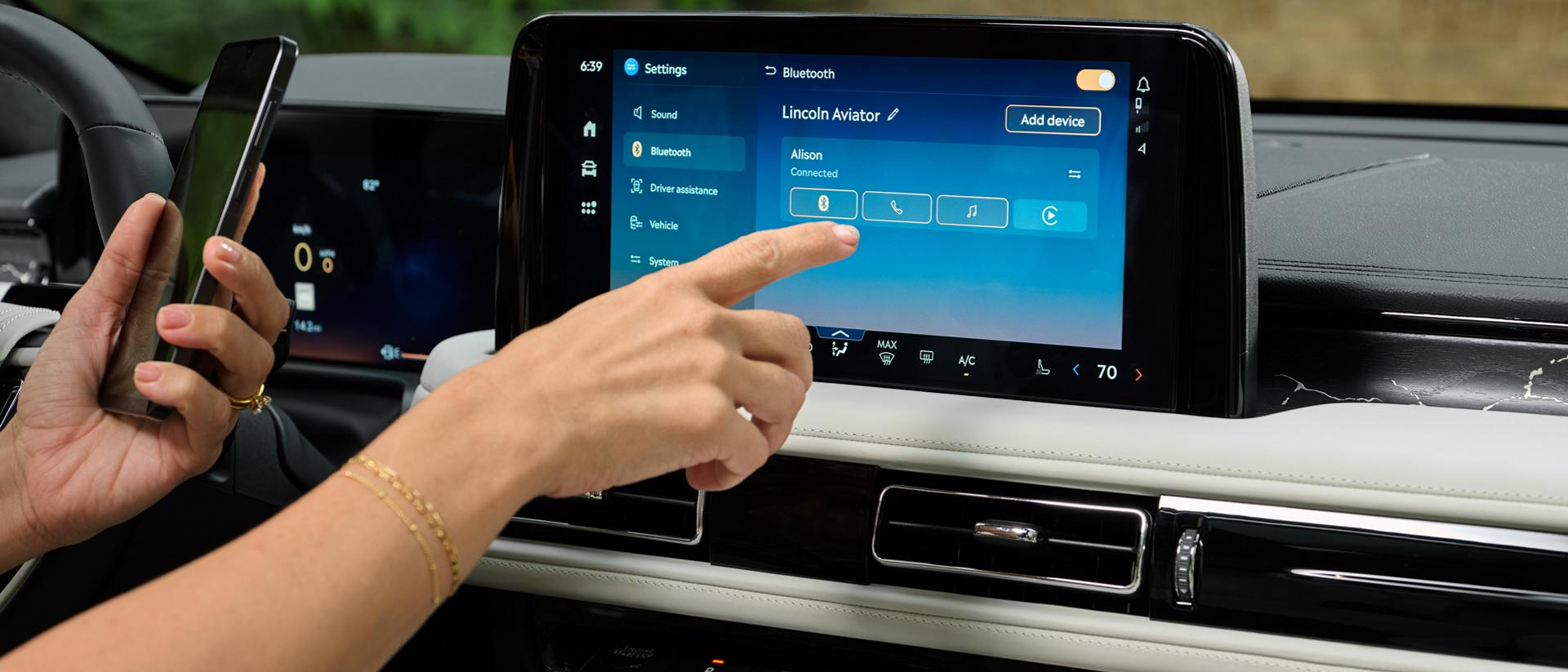 Une main tendue pour interagir avec l’écran tactile central d’un Lincoln Aviator® 2027