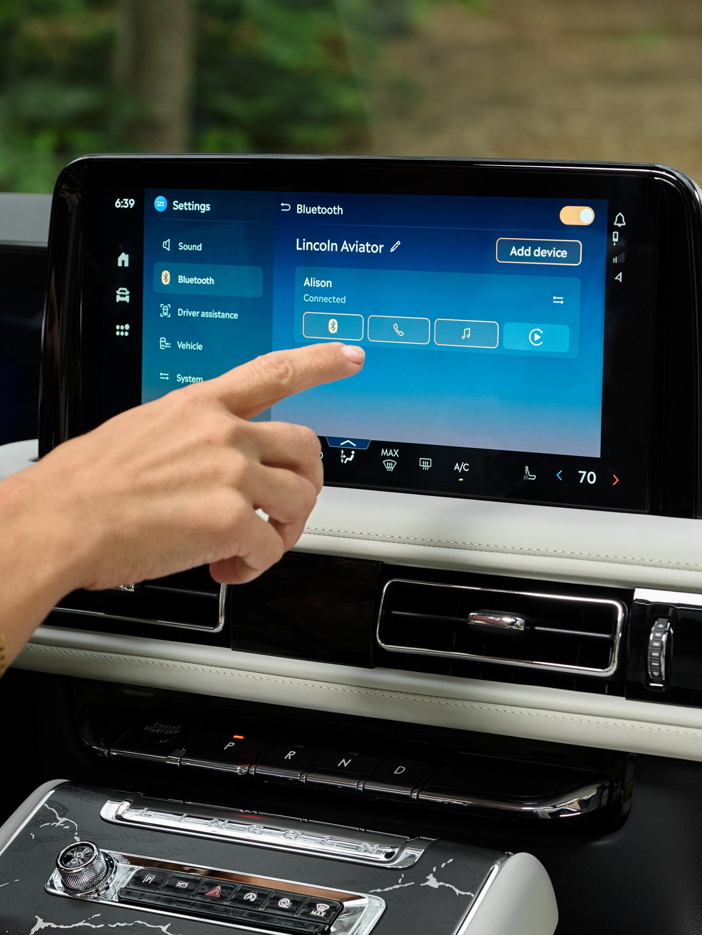 Une main tendue pour interagir avec l’écran tactile central d’un Lincoln Aviator® 2027