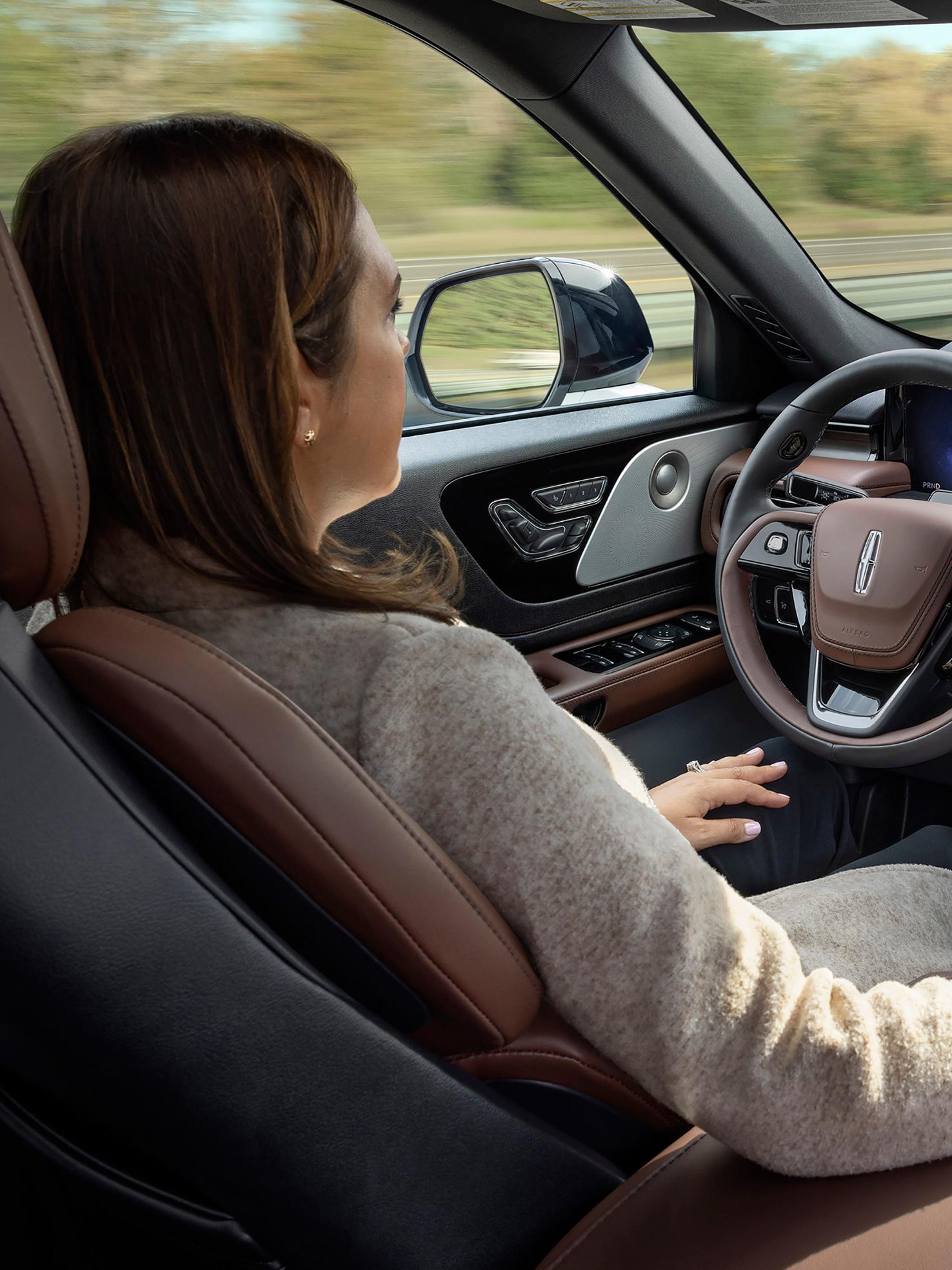 Une femme conduit un Lincoln Aviator® 2026 en mode mains libres, les yeux rivés sur la route, grâce au système Lincoln BlueCruise