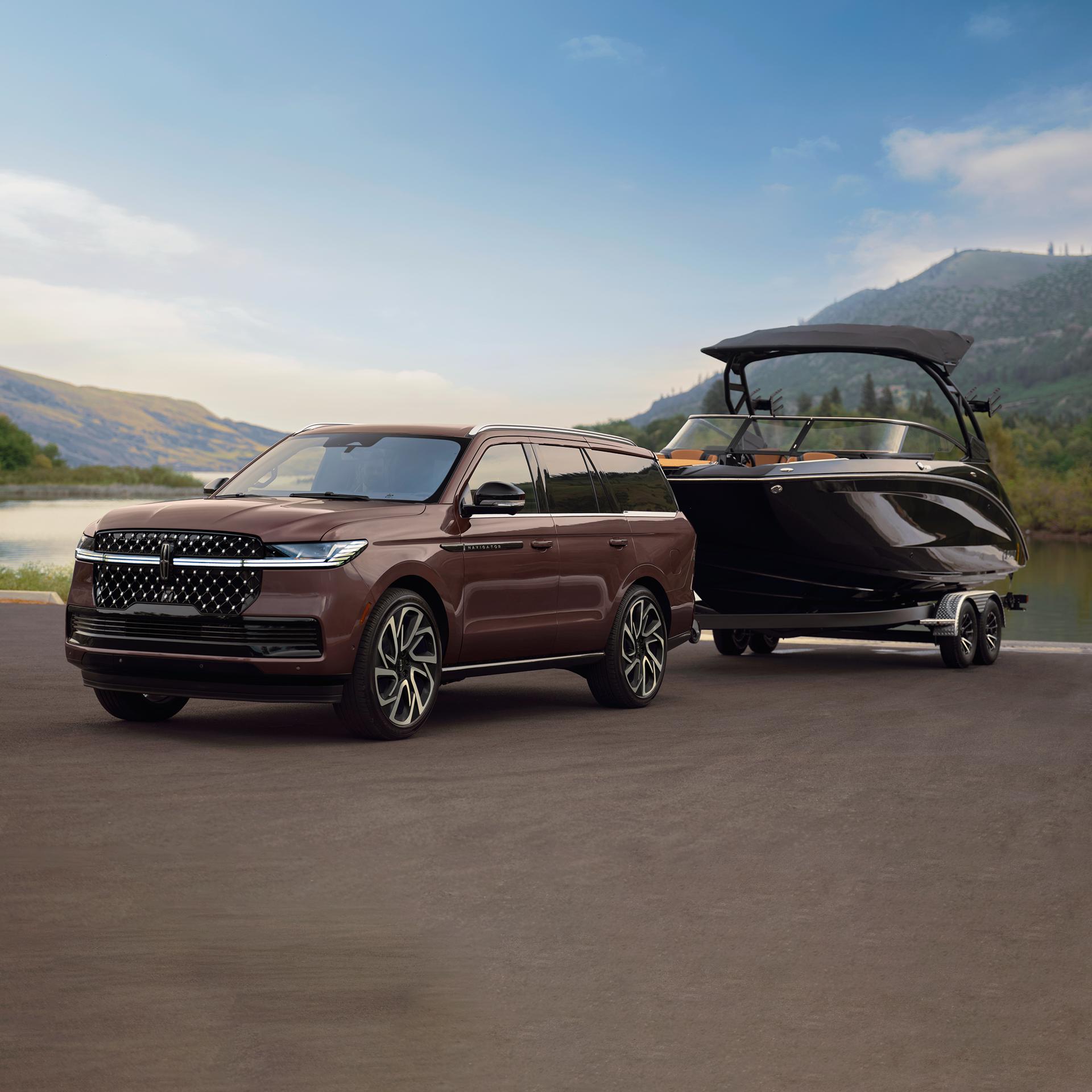 Un modèle Lincoln Navigator® Black Label™ 2027 est stationné devant un bord de mer pittoresque avec un bateau de plaisance attelé