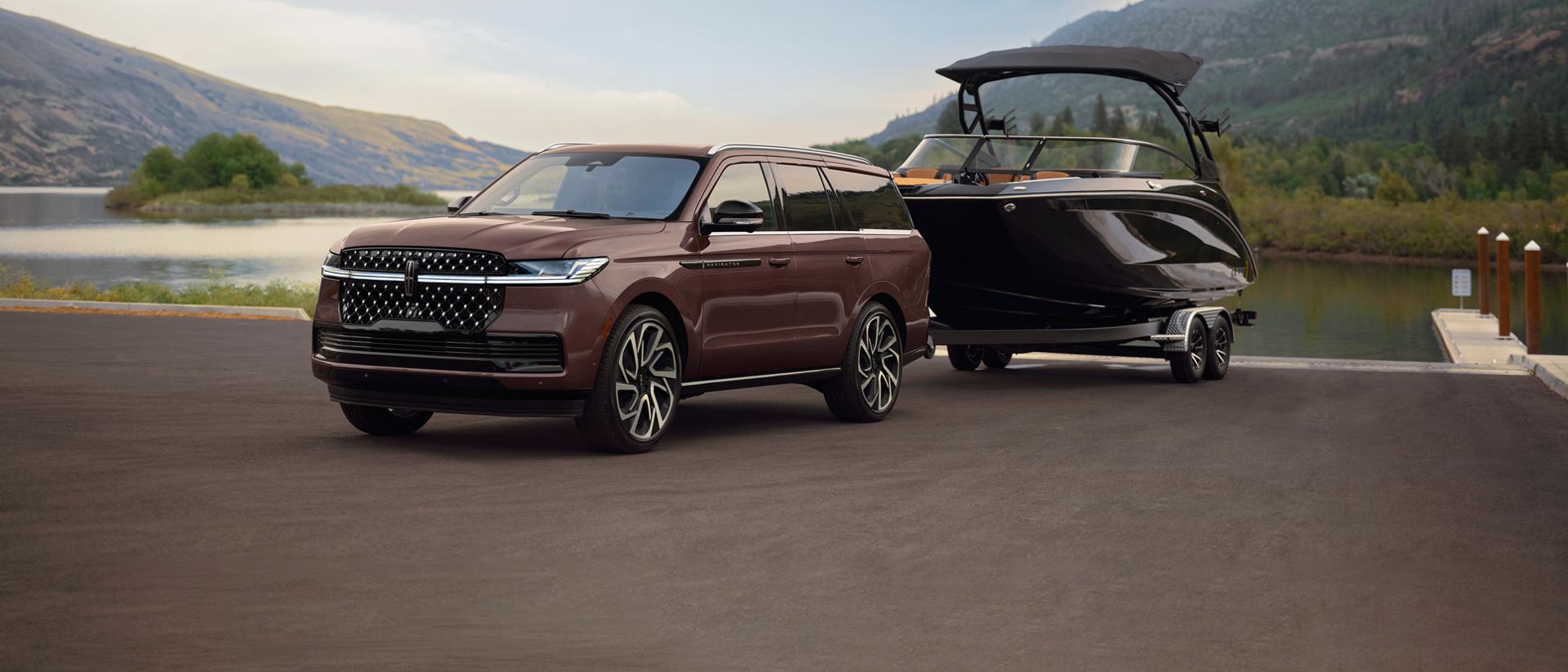 Un VUS Lincoln Navigator® 2027 avec un bateau sur une remorque est stationné sur une rampe de mise à l’eau panoramique.
