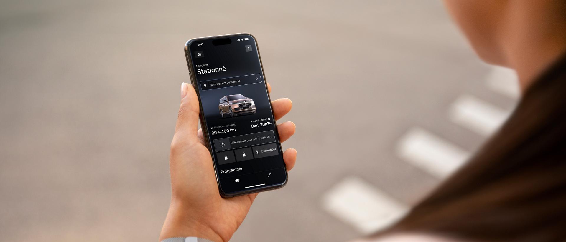 Une personne tenant un téléphone mobile affichant l’application Lincoln.