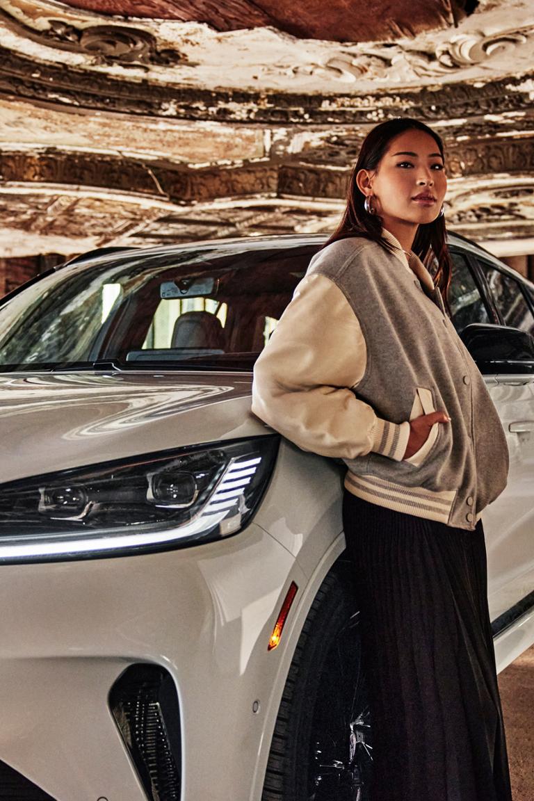 Une femme appuyée sur un véhicule Lincoln blanc