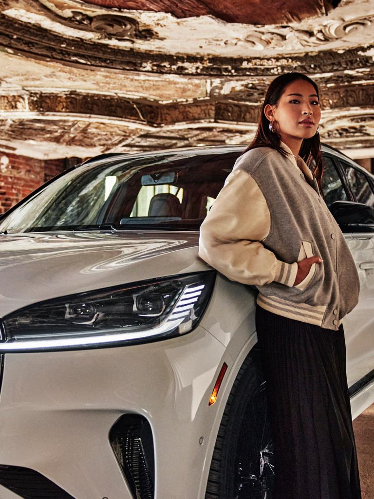 Une femme appuyée sur un véhicule Lincoln blanc