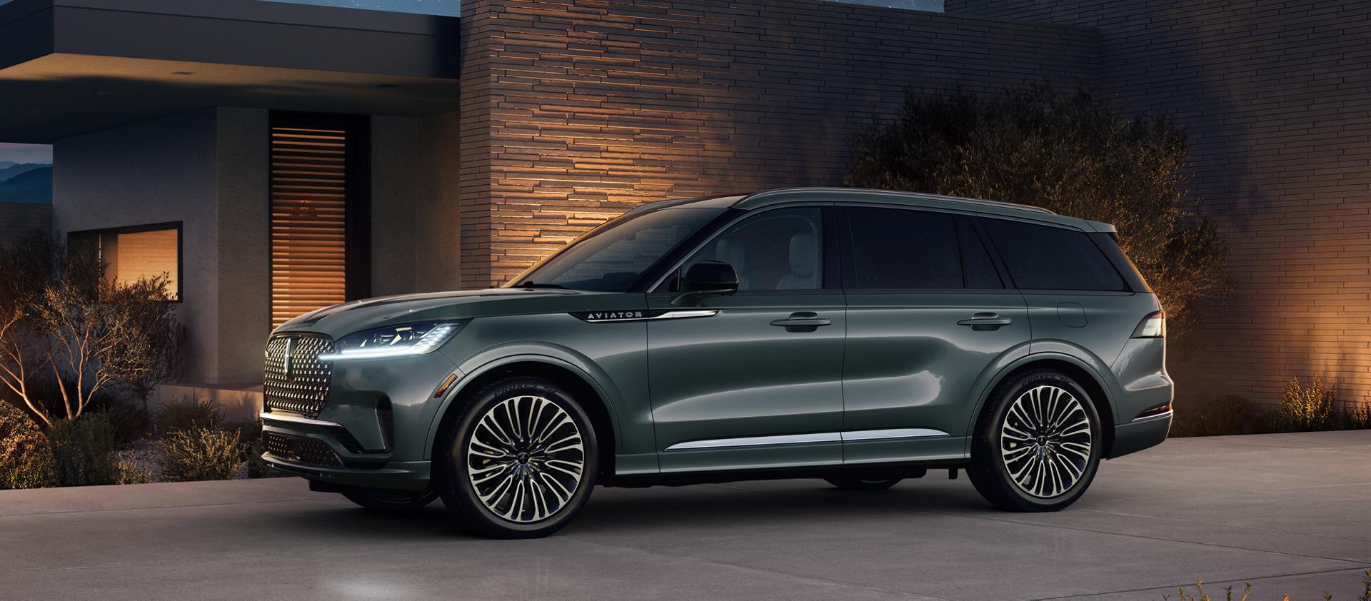 Un Lincoln Aviator® Black Label® 2027 stationné à côté d’une maison moderne la nuit