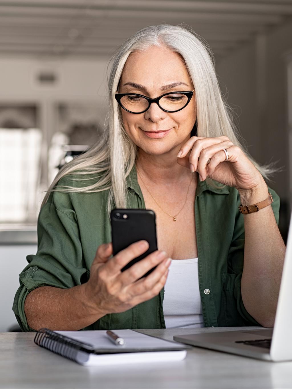 Une femme assise à un bureau, regardant son téléphone portable