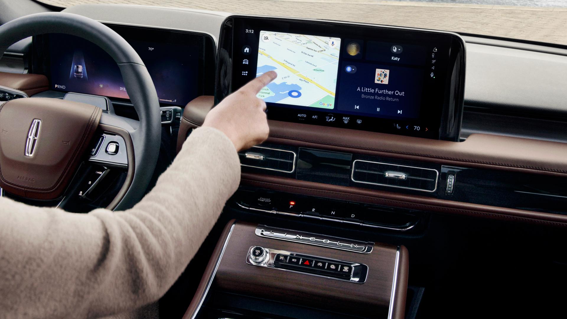 Le passager avant touche l’écran central à l’intérieur d’un Lincoln Aviator® 2027