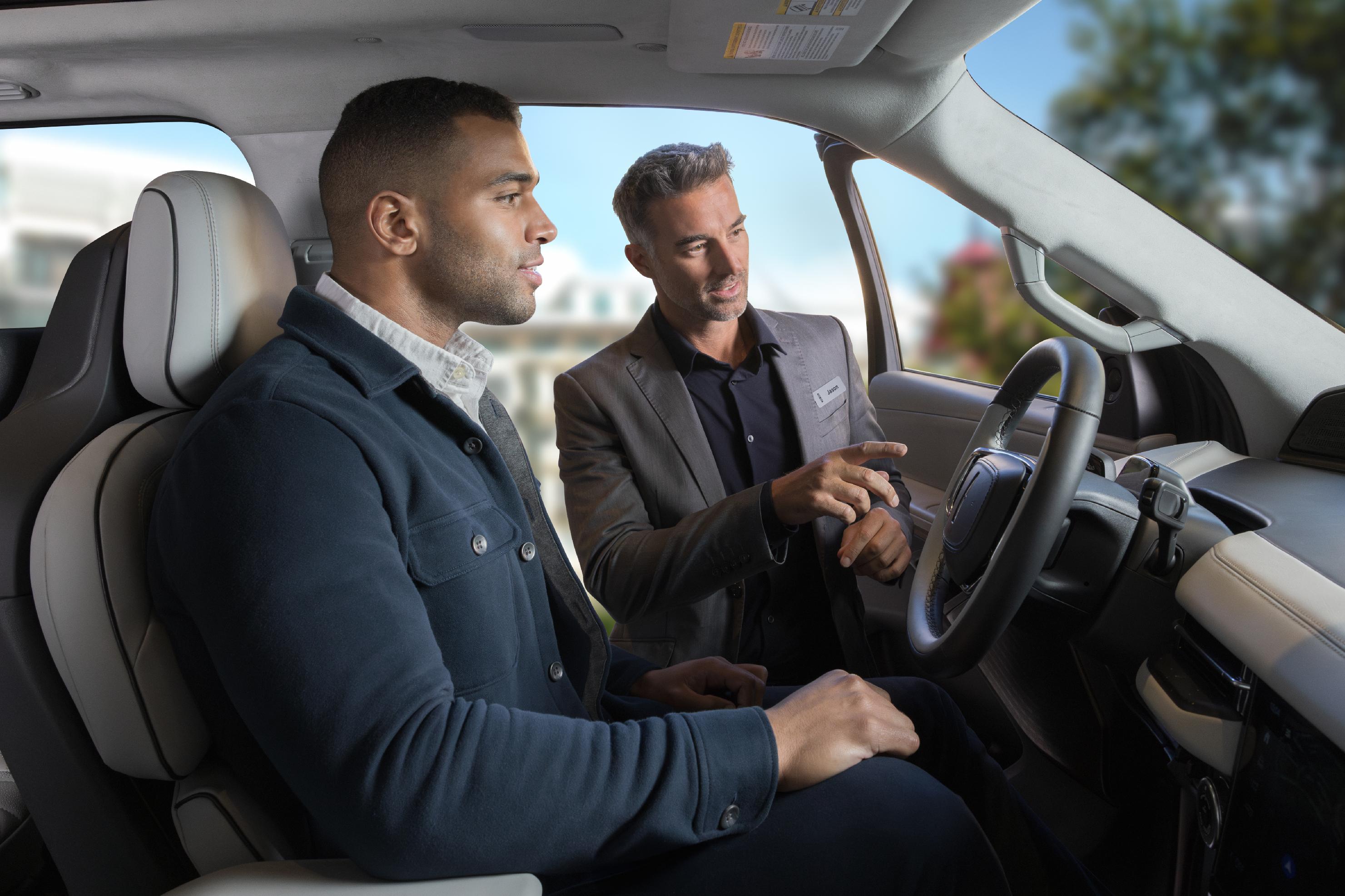 Un représentant des ventes Lincoln montrant à un client une caractéristique à l’intérieur du véhicule Lincoln.