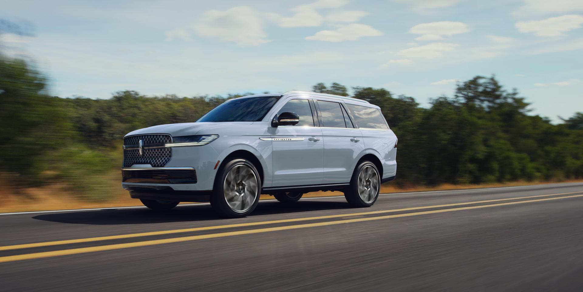 Un véhicule Lincoln Navigator® Black Label™ 2027 est stationné devant un bord de mer pittoresque avec un bateau de plaisance attelé