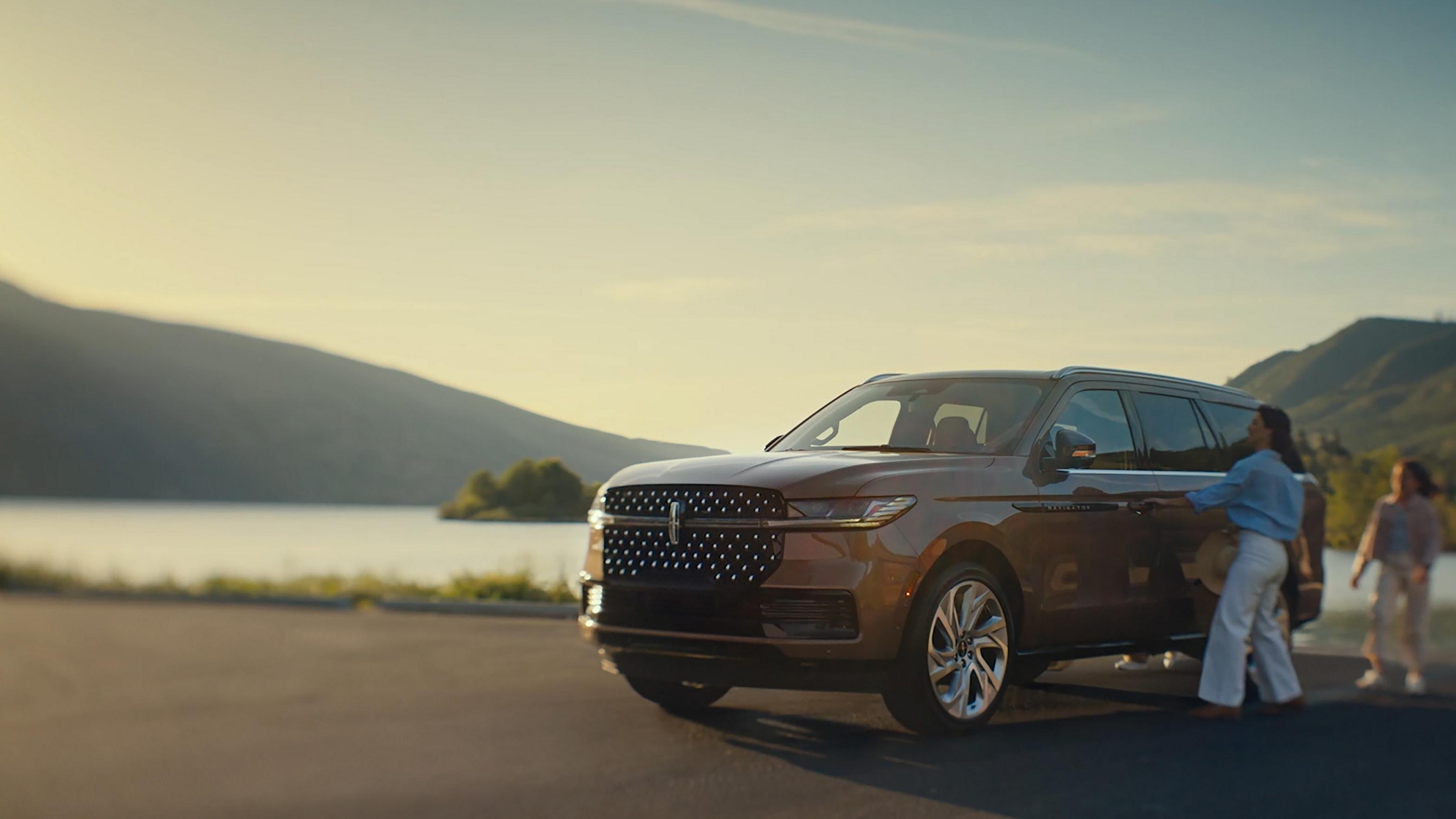 Une famille s’approche d’un Lincoln Black Label Navigator® 2026 alors que la séquence d’éclairage Embrace commence